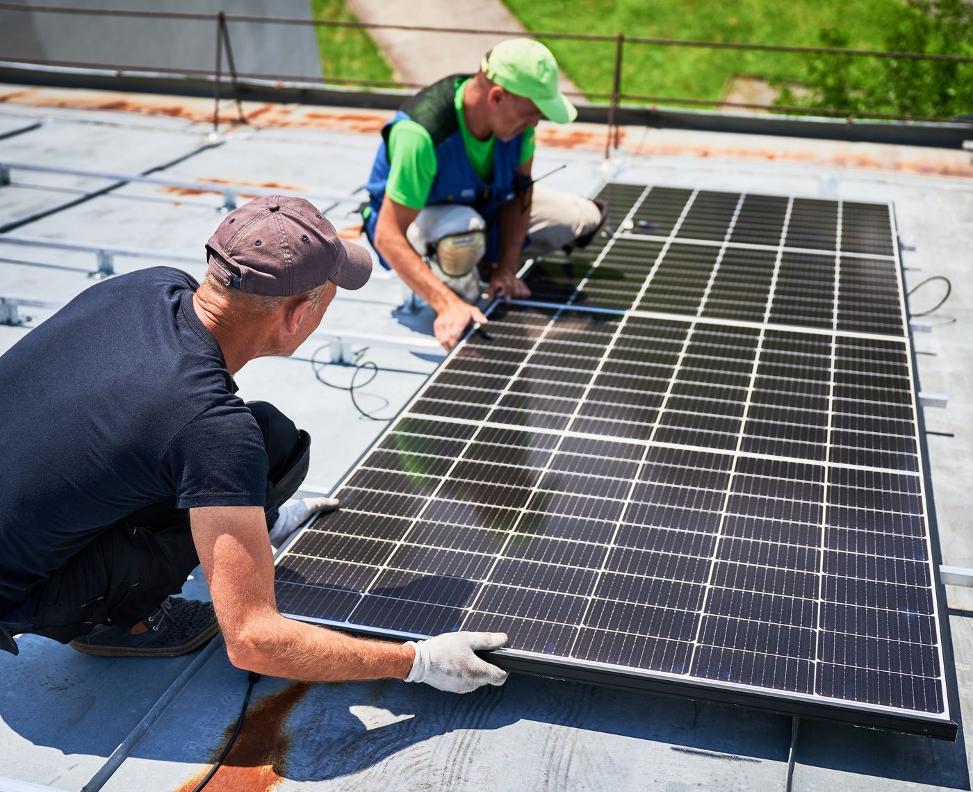 Deux installateurs posent un module photovoltaïque sur une toiture plate